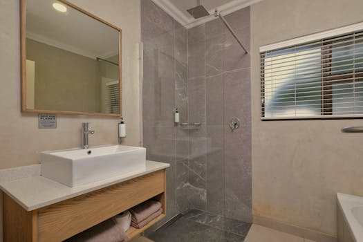 A sleek, contemporary bathroom design featuring a glass walk-in shower and wooden vanity unit.